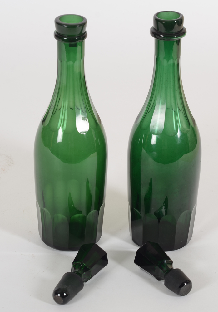 Two early emerald green cut glass decanter bottles, probably England, 19th century — The bottles open