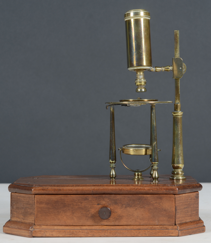 Antique microscope — The brass microscope mounted on a mahogany or walnut base with drawer