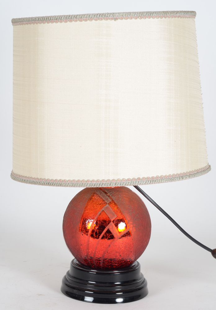 A stunning red acid etched glass art deco lamp on a black glass base, 1930's — the lamp during daylight